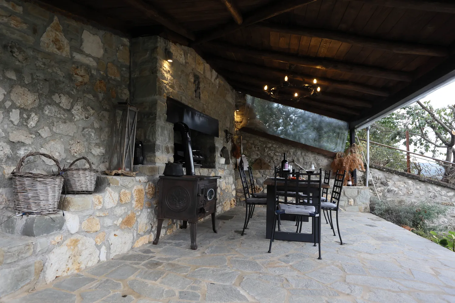 Η πέτρινη βεράντα με τη σόμπα και τα καλάθια